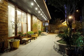 An outdoor patio area with wooden flooring, potted plants, and outdoor seating. - Pupeng Boutique Hotel (Yangbi)