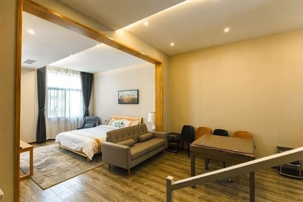 A hotel room with a bed, sofa, dining table, and chairs.