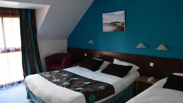 A hotel room with a large bed, a chair, a nightstand with a phone, and a painting on the wall.