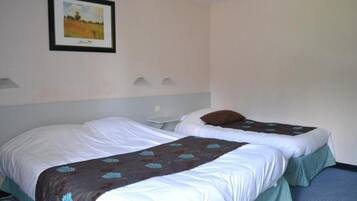 A hotel room with two beds, a framed picture on the wall, and a small table.