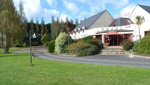 Un hotel con ristorante, ingresso rosso e giardino curato.