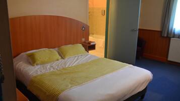 A hotel room with a bed, a bedside table, and a bathroom visible through an open door.