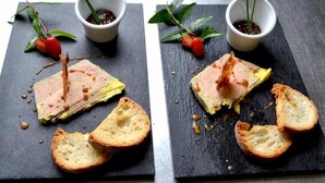 Due lavagne nere squadrate in ardesia con cibo e pane, ognuna affiancata da una piccola ciotola bianca con una pianta.