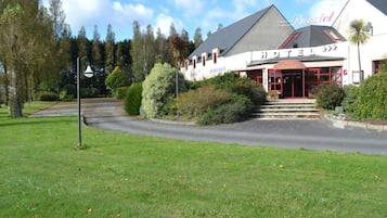 A hotel with a restaurant, a red entrance, and a well-maintained garden.
