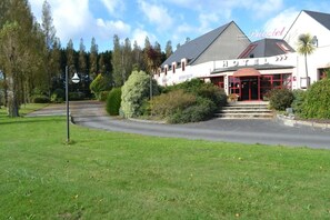 A hotel with a restaurant on the ground floor, surrounded by greenery and trees. - Logis Hotel Lucotel (Lanvollon)