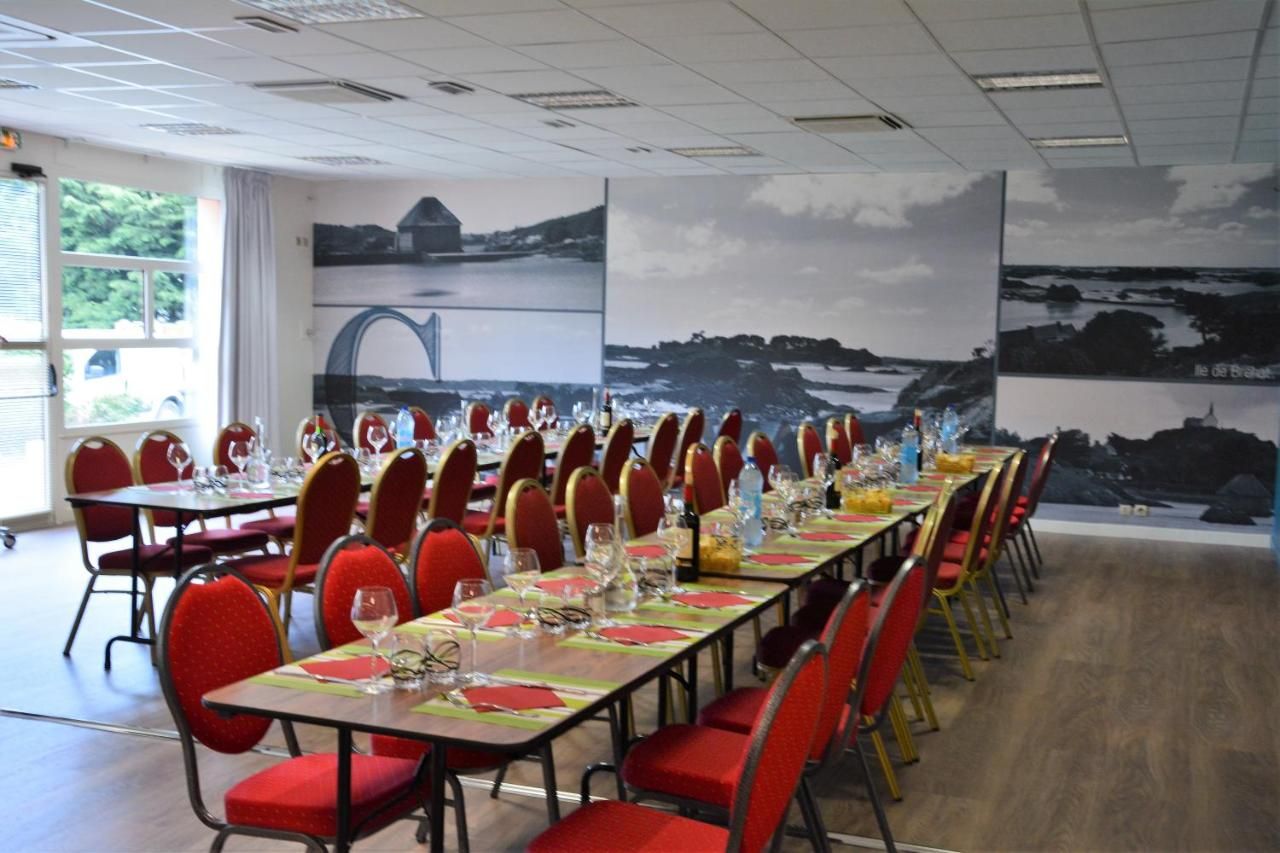 A conference room with long tables set for a meeting, red chairs, and a scenic mural on the wall.