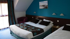 Una camera d'albergo con un letto grande, una sedia, un comodino con il telefono e un quadro appeso al muro.