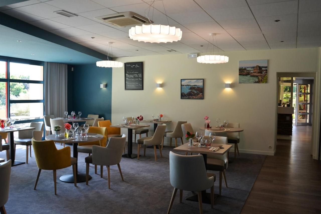A restaurant with multiple tables and chairs, a chalkboard menu, and wall-mounted lights.