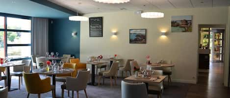 Ein Restaurant mit mehreren Tischen und Stühlen, einer Kreidetafel und Wandleuchten.
