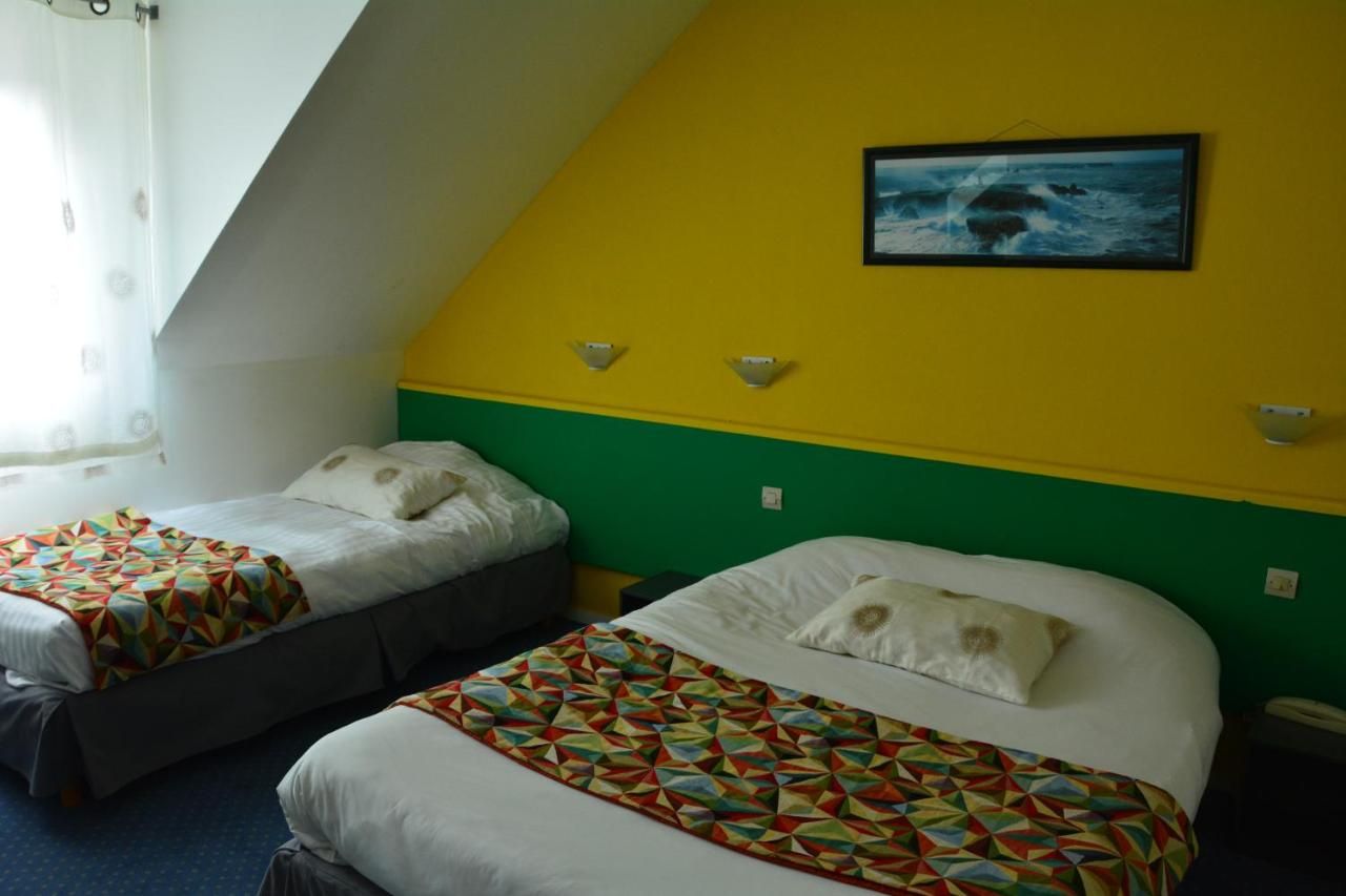 A hotel room with two beds, a green and yellow wall, a framed picture of the ocean, and a window with curtains.