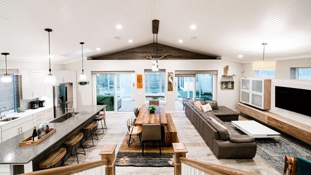 A spacious living area with a large wooden dining table, a sofa, and a TV. - Family Tide Retreat/Heated Pool & 2 Spas (St. Augustine)
