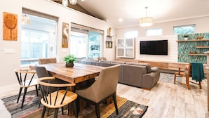 A spacious living room with a wooden dining table, comfortable seating, a large TV, and a view of the outdoors. - 2 Masters-Heated Pool & Spa+1 min Walk to Beach (St. Augustine)