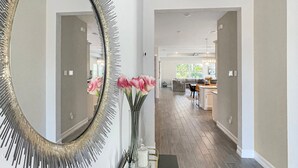 A modern hallway with a large mirror, a vase with flowers, and a black console table. - Luxurious Retreat in Naples Reserve! 3 Bedroom Pool House, unwind in style! (Naples)