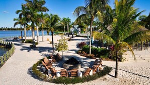 A beachside resort with a circular seating area, palm trees, and a view of the ocean. - Luxurious Retreat in Naples Reserve! 3 Bedroom Pool House, unwind in style! (Naples)
