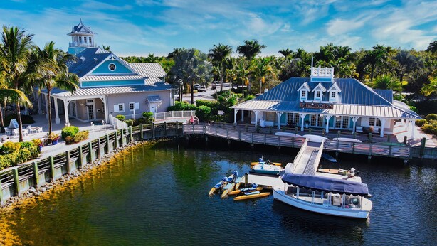 A waterfront property with a dock, a boat, and a building with a sign that reads "GULF CAFE". - Luxurious Retreat in Naples Reserve! 3 Bedroom Pool House, unwind in style! (Naples)