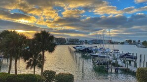 A marina with boats docked, a waterfront view, and a sunset in the background. - Modern large 2 bedroom/2 bath Condo on Intercoastal with gorgeous  sunset views (St Pete Beach)
