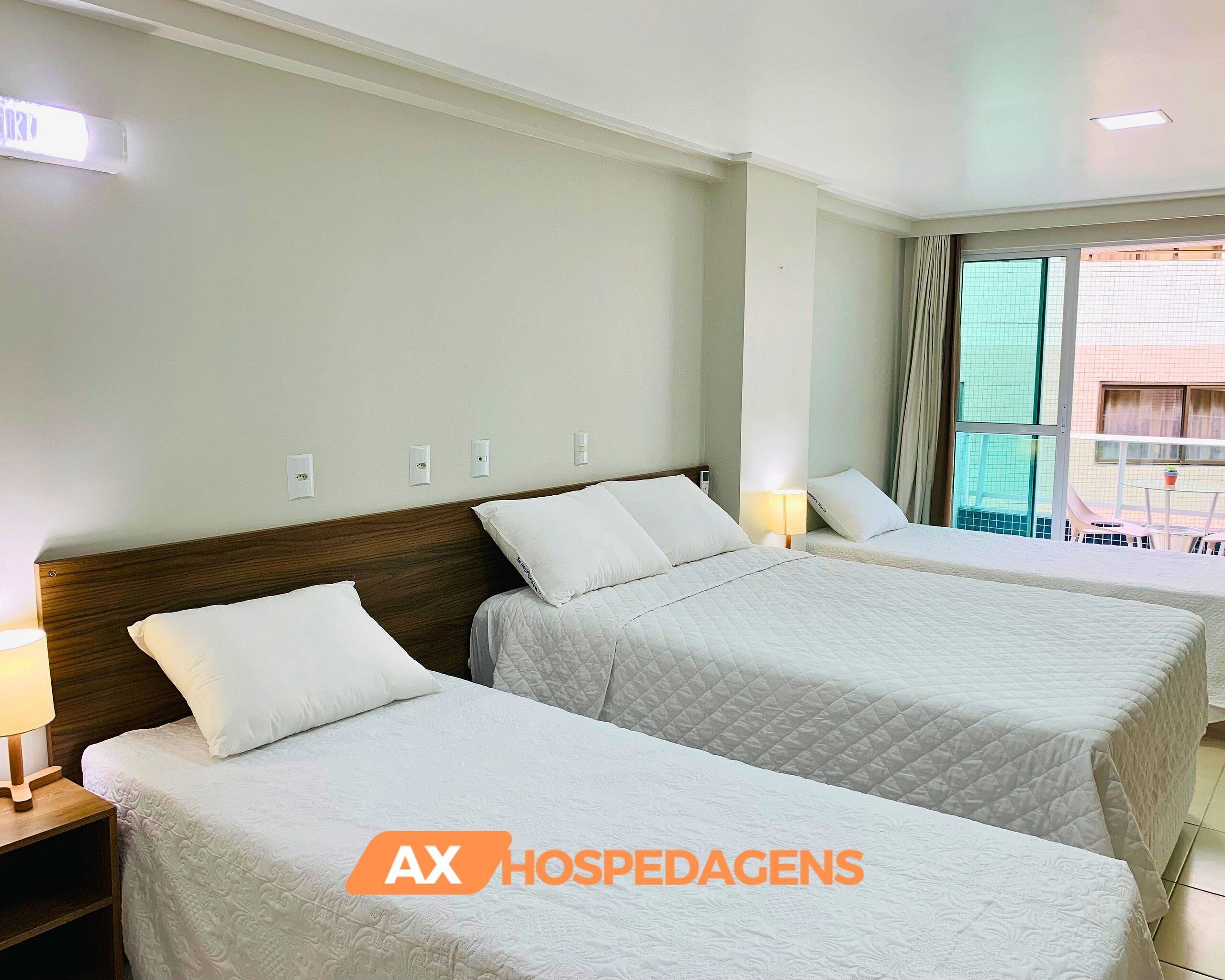 A hotel room with two beds, a wooden headboard, bedside lamps, and a window with a view of the outside.