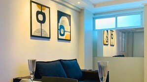Una sala de estar moderna con un sofá, una mesa de comedor con mantel blanco y dos obras de arte abstracto enmarcadas en la pared.