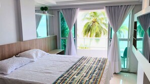 Una habitación de hotel moderna con una cama grande, un televisor y un balcón con vistas a palmeras.