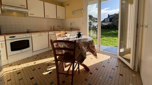 A kitchen with a dining table, chairs, and a view of the outdoors through a sliding glass door.