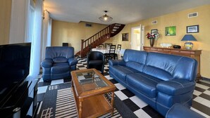 A living room with a checkered floor, a sofa, a chair, a coffee table, and a TV.