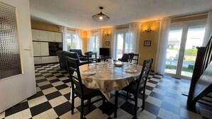 A dining area with a checkered floor, a round table set for four, and a kitchen in the background.