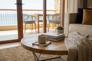 A round wooden table with a coffee mug, a book, and a small plant.