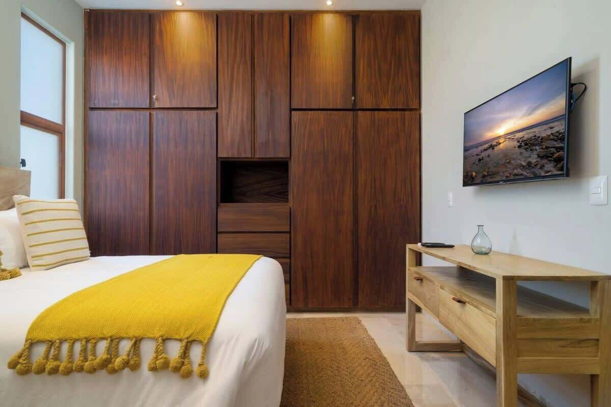 Una camera da letto con un letto, un'armadietto in legno, una TV e un comodino.