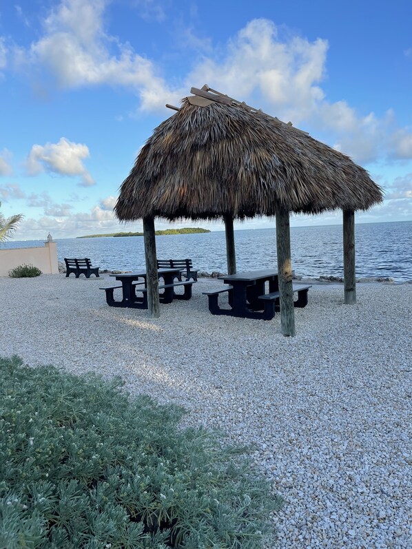 A beachside gazebo with picnic tables, surrounded by pebbles and overlooking the sea. - Coastal Beach Home in the heart of Key Largo. (Key Largo)