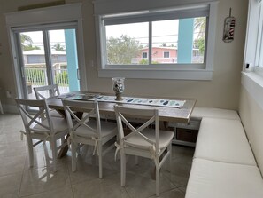 A dining area with a table and chairs, a vase with stones, and a view of the outside. - Coastal Beach Home in the heart of Key Largo. (Key Largo)
