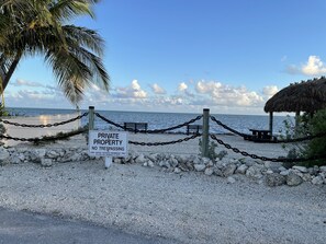 A private property sign, a beach, a palm tree, and a thatched structure. - Coastal Beach Home in the heart of Key Largo. (Key Largo)