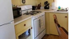 Una cuina compacta amb fogó, microones i armaris.