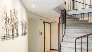 Ein Flur mit Treppe, einer Tür und Wandbildern.