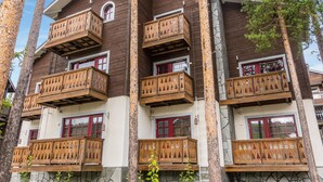 Ein mehrstöckiges Gebäude mit Balkonen, versehen mit Holzgeländern und Fenstern mit roten Rahmen.