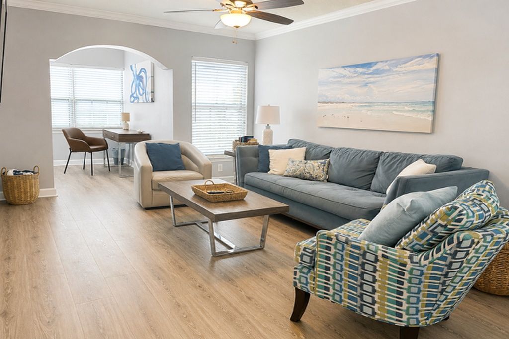 A living room with a sofa, armchair, coffee table, and a dining area with a chair and table.