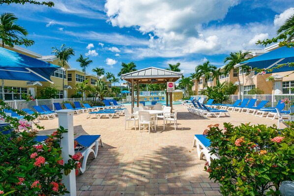 A poolside area with lounge chairs, a covered seating area, and a pool.
