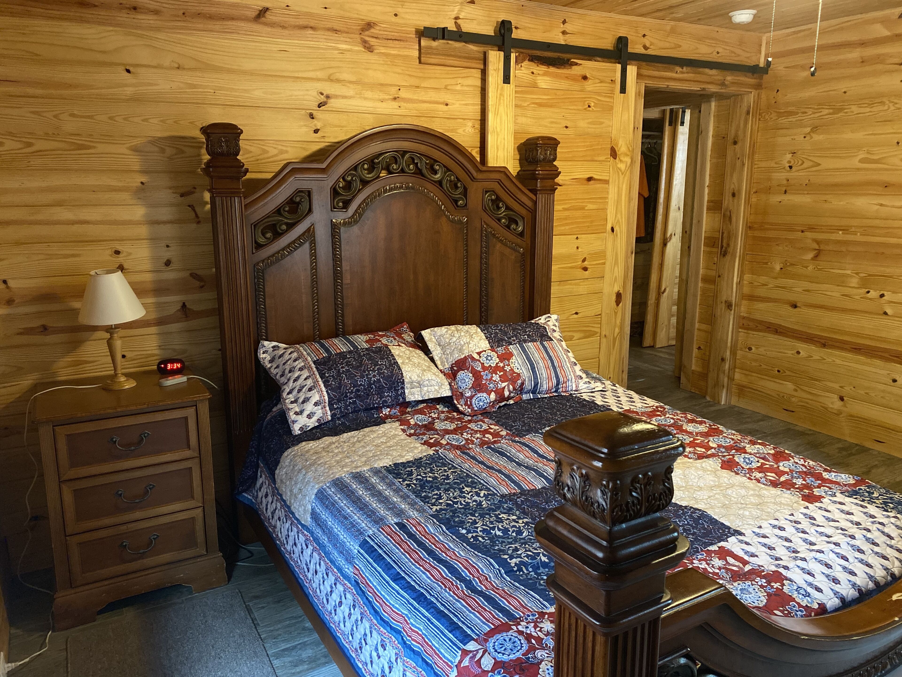 Een slaapkamer met houten lambrisering, een groot bed, een nachtkastje en een dressoir.