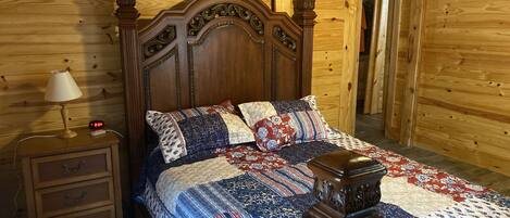 Een slaapkamer met houten lambrisering, een groot bed, een nachtkastje en een dressoir.