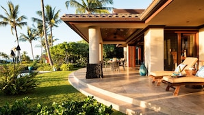 A resort with a covered patio, outdoor seating, and palm trees. - Stunning Villa with Ocean Views, Pool, Home Theatre + Resort Amenities (Kamuela)