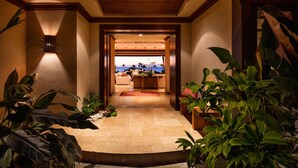 A hallway leading to a room with a view of the ocean, featuring a wooden ceiling, tiled floor, and potted plants. - Stunning Villa with Ocean Views, Pool, Home Theatre + Resort Amenities (Kamuela)