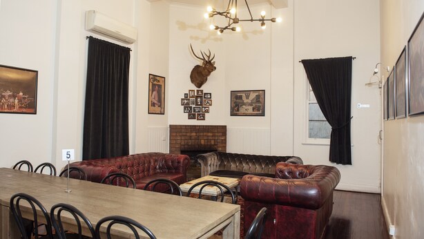 Un coin repas avec une table et des chaises en bois, une cheminée et une tête de cerf accrochée au mur.