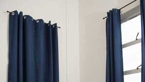 Une chambre à coucher avec un lit, du linge de lit blanc et des rideaux bleus.