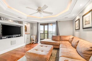 Relax in this stylish living room with a large flat-screen TV, comfortable sofa, and ceiling fan.