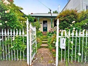 Een huis met een voortuin, een pad naar de ingang en een veranda met een groen dak.