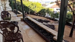 A patio area with a garden bed, outdoor furniture, and a view of the surrounding area. - Historic 3-Bed 'Bostane Cottage' 5 minutes to City. (West Hobart)