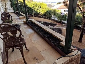A patio area with a garden bed, outdoor furniture, and a view of the surrounding area.
