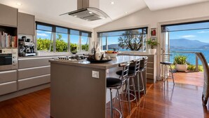 A modern kitchen with a large island, bar stools, and a view of the sea. - "Casa Con Vista" Luxury Waterfront Home-Sleeps 10. (Tranmere)