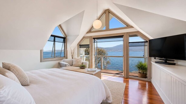 A bedroom with a large bed, a TV, and a view of the sea. - "Casa Con Vista" Luxury Waterfront Home-Sleeps 10. (Tranmere)