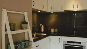 Cozinha com armários brancos, forno embutido e piso de madeira.