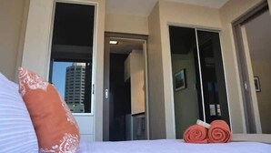 Quarto de hotel com cama, janela e porta que dá para uma varanda.